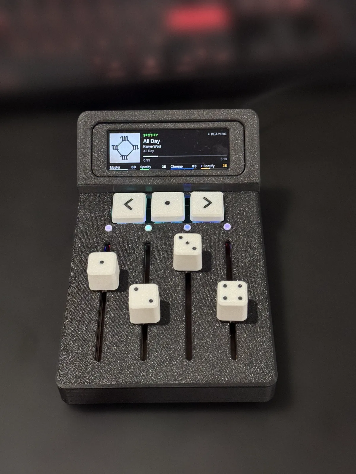Trackside from above: now-playing screen, three keys, four LEDs and four dice-capped faders.